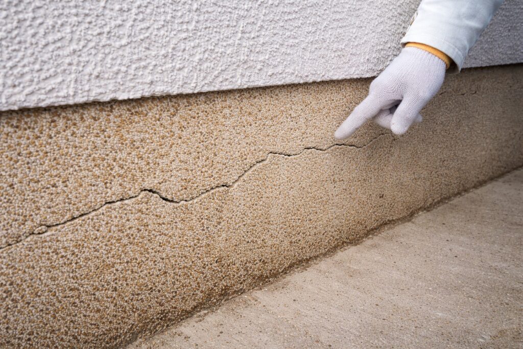 基礎コンクリートに発生した横方向のひび割れを指で示している様子