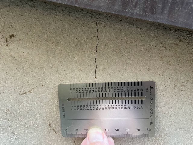 クラックスケールで基礎の危険なひび割れ幅（0.5mm以上）を計測する点検作業